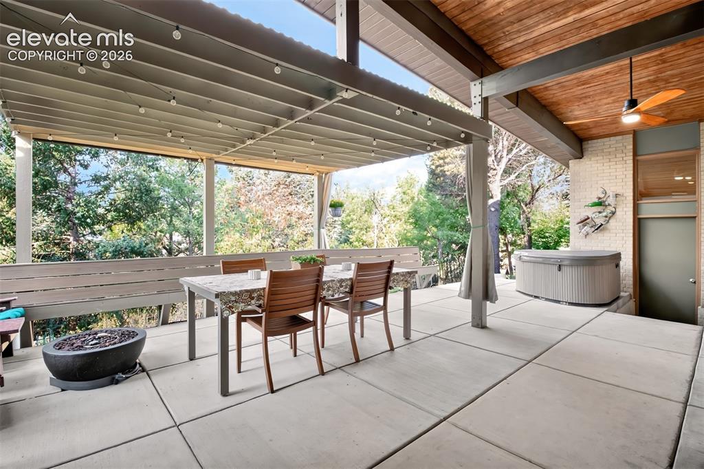 Image 22 of 49: A view of the patio showing the fire pit and the hot tub that are included!