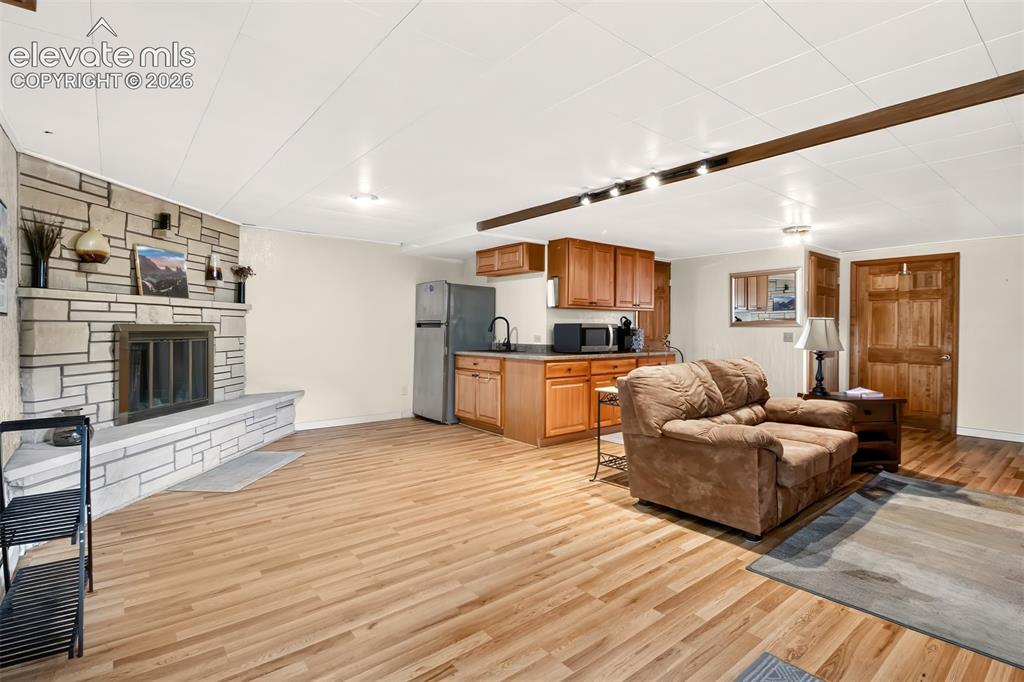 Image 38 of 49: A view of the basement living room with fireplace andkitchenette with lamin