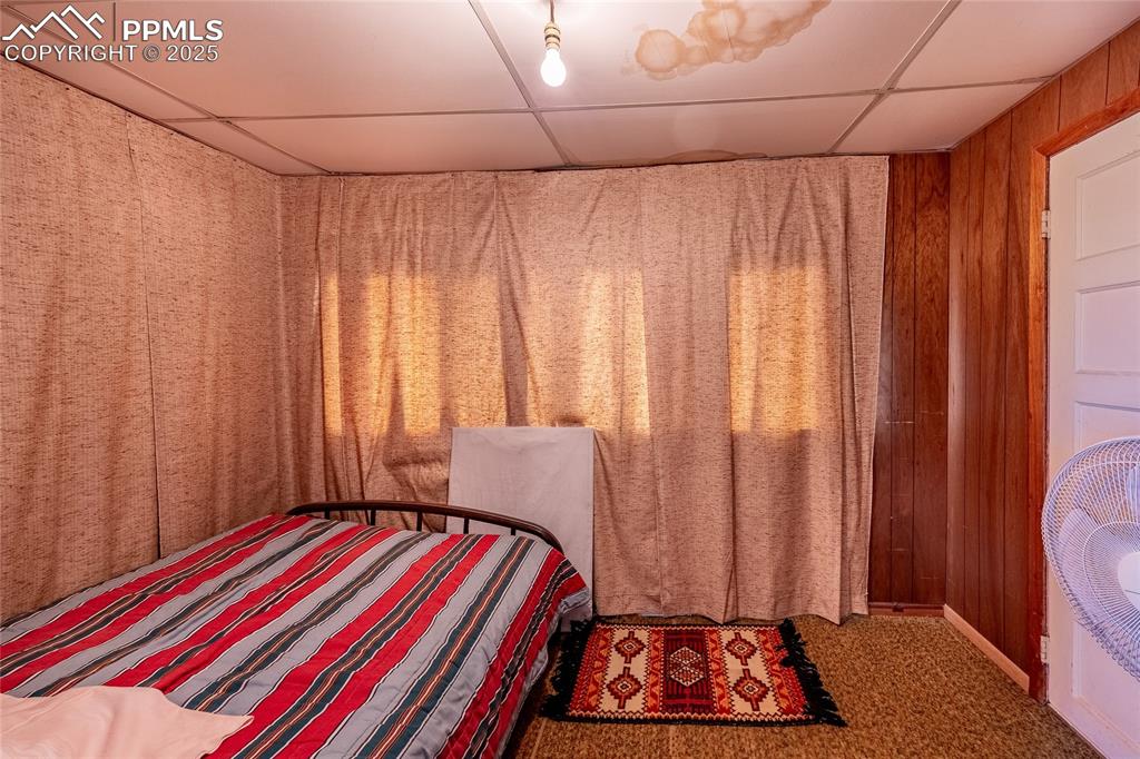 Image 12 of 21: Bedroom featuring a paneled ceiling and wooden walls