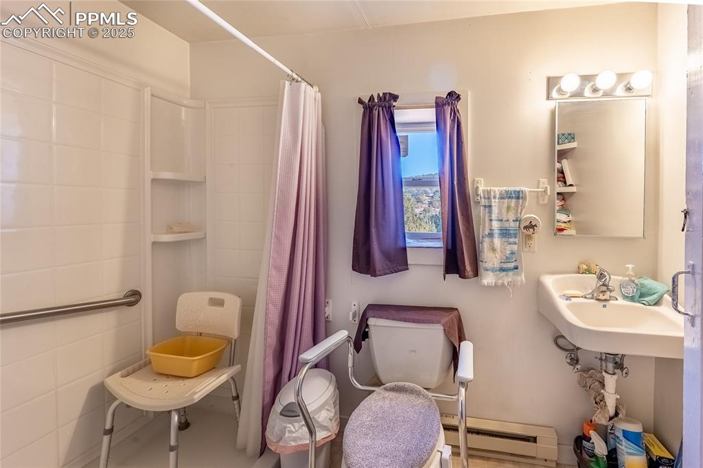 Image 14 of 23: Bathroom with a baseboard radiator and a shower with shower curtain