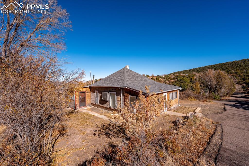 Image 16 of 21: View of side of property featuring roof with shingles and a patio area