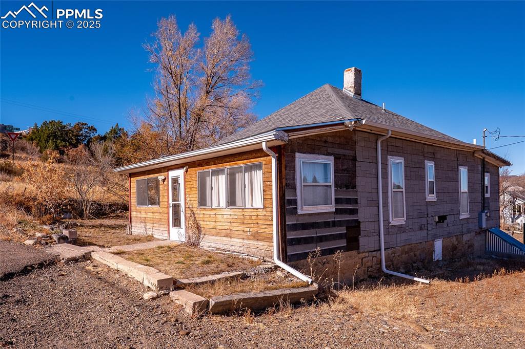 Image 2 of 21: View of side of home featuring a chimney and a shingled roof