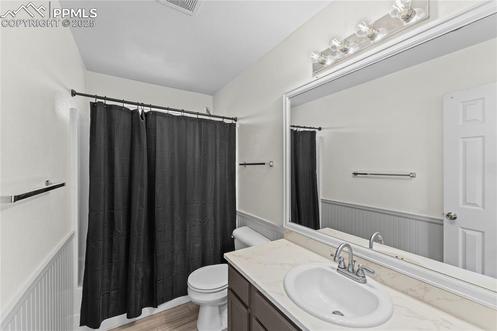 Image 10 of 29: Full bathroom featuring a wainscoted wall, vanity, wood finished floors, an