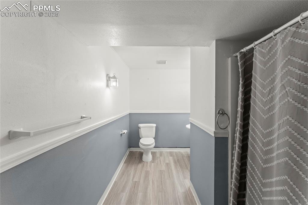 Image 21 of 29: Full bath featuring a textured ceiling, wood finished floors, and curtained