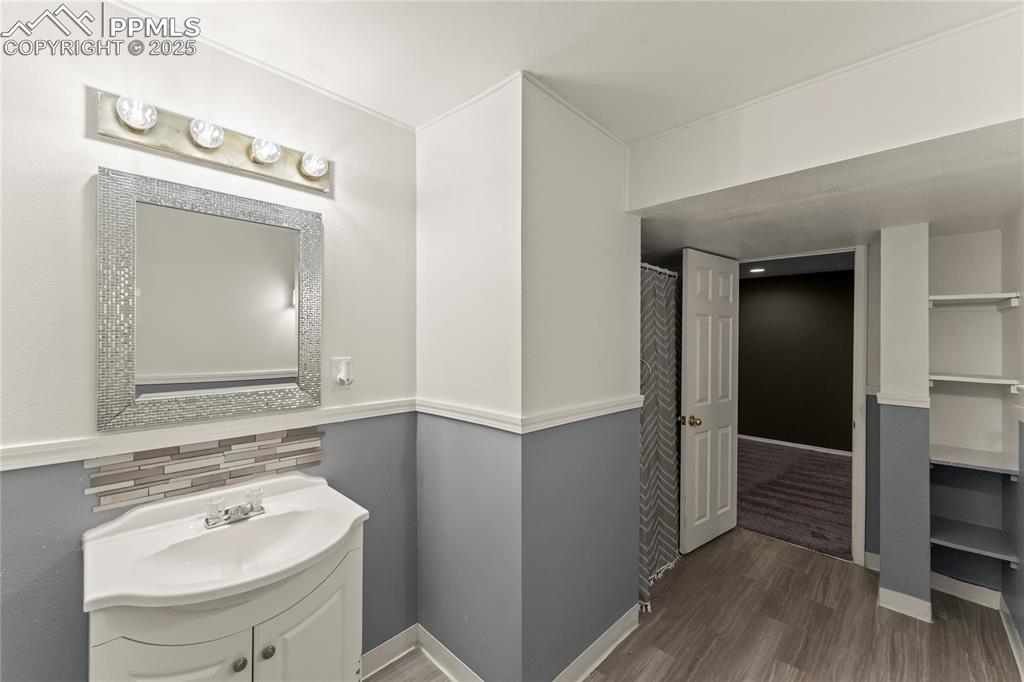 Image 22 of 29: Bathroom with vanity, wood finished floors, and tasteful backsplash