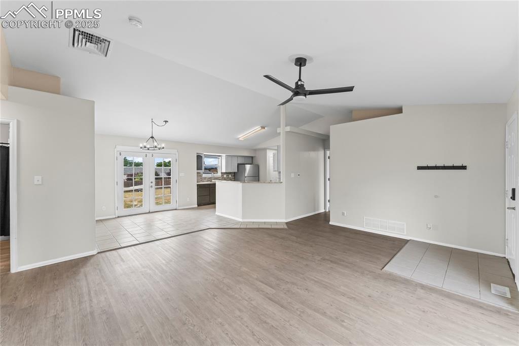 Image 4 of 29: Unfurnished living room with vaulted ceiling, ceiling fan, wood finished fl