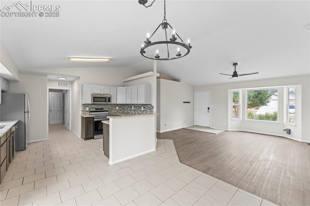 Image 5 of 29: Kitchen with decorative backsplash, lofted ceiling, a ceiling fan, stainles