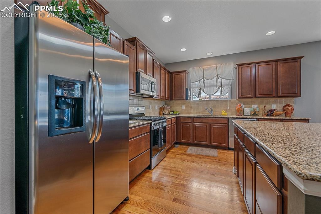 Image 14 of 49: Kitchen with stainless steel appliances, light wood finished floors, backsp