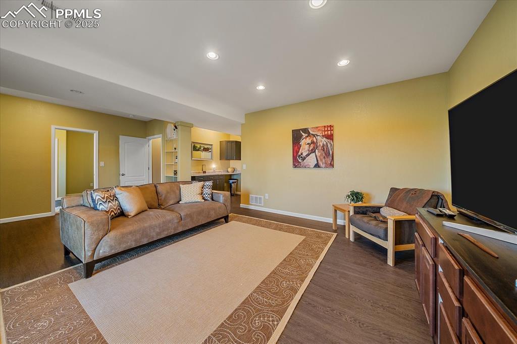 Image 33 of 49: Living room with recessed lighting and dark wood finished floors