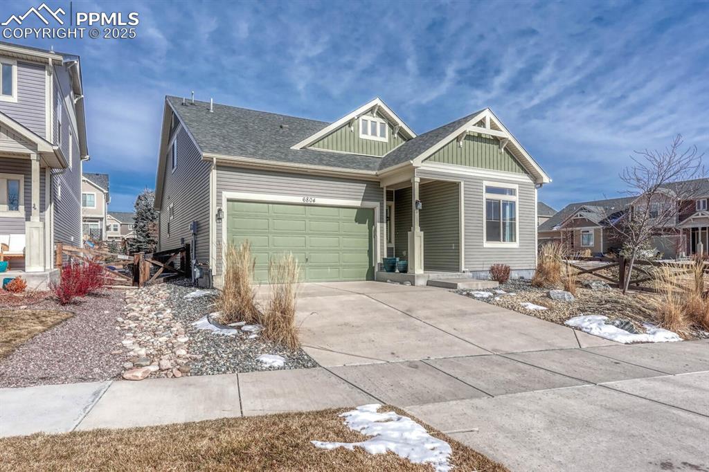 Image 3 of 35: View of front facade with driveway, a shingled roof, a garage, and board an