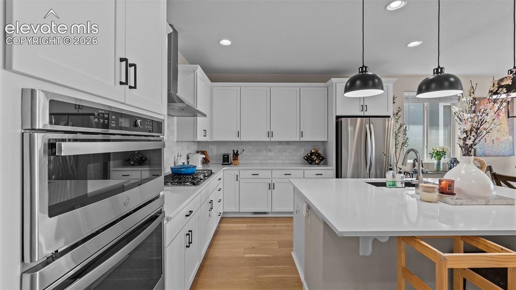 Image 13 of 46: Kitchen featuring white cabinetry, stainless steel appliances, wood-finish 