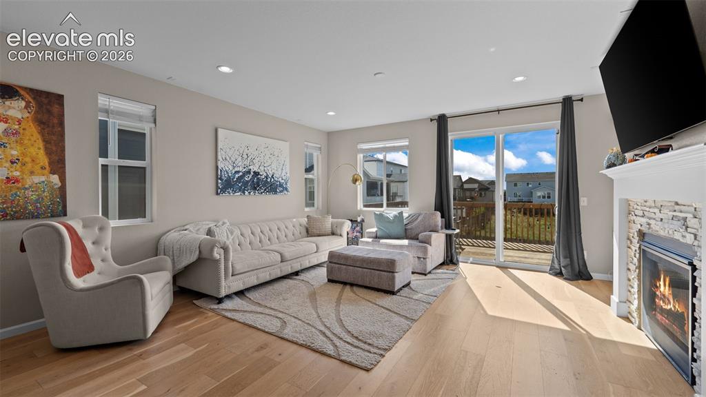 Image 15 of 46: Hardwood-finish flooring, recessed lighting, and a fireplace with a stacked