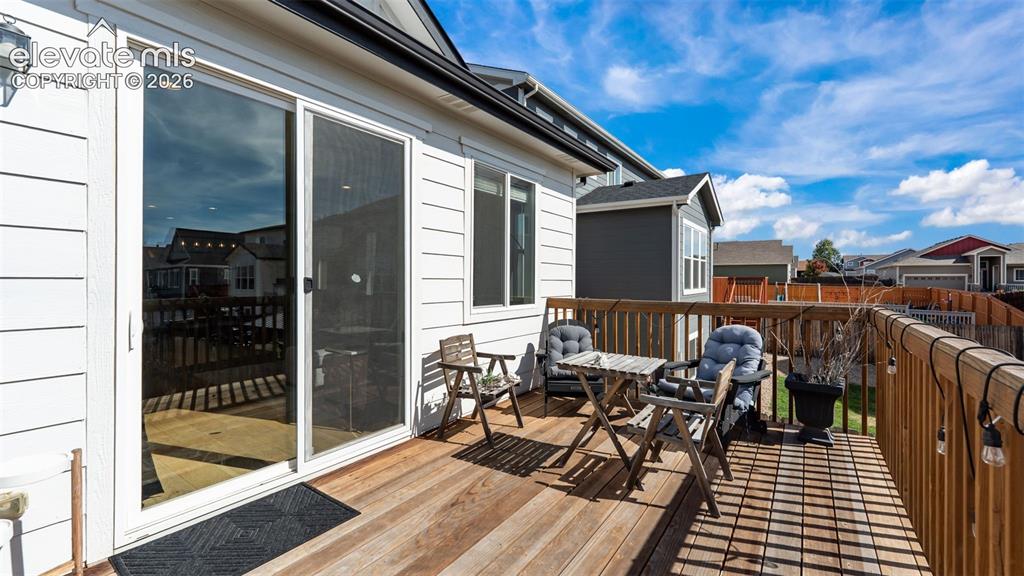 Image 18 of 46: Expansive wood-plank deck with a full railing, white horizontal siding, and