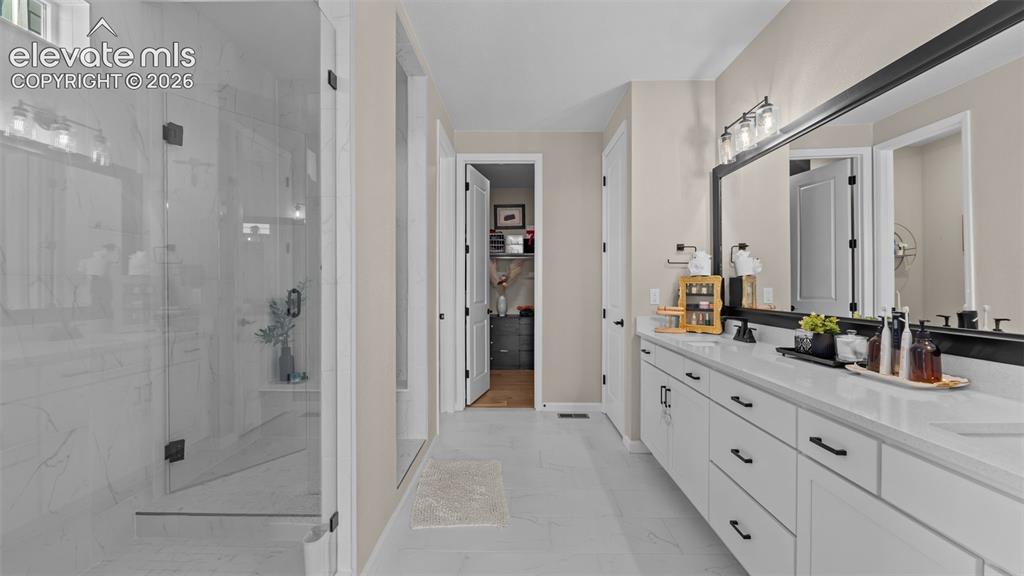 Image 22 of 46: Dual vanity with white cabinetry, matte black hardware, and an expansive mi
