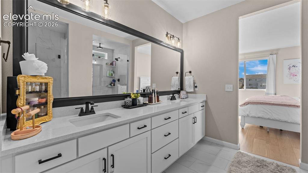 Image 24 of 46: Dual sink vanity with white cabinetry, quartz-finish countertop, and matte 