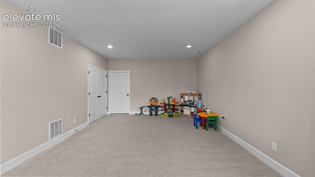 Image 29 of 46: Spacious room with neutral wall tones and recessed lighting