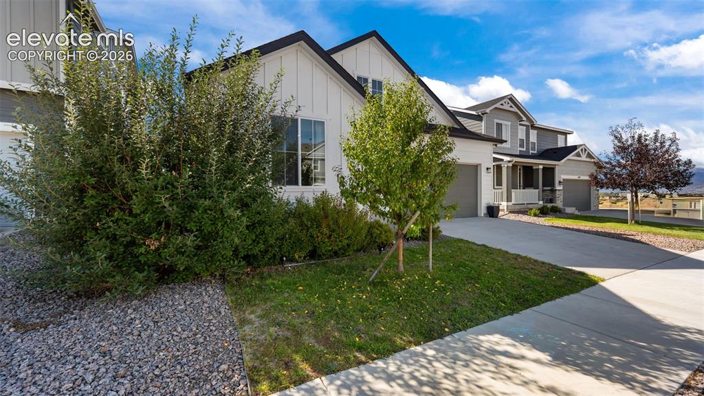 Image 3 of 46: White vertical siding facade with black trim, concrete driveway, attached t