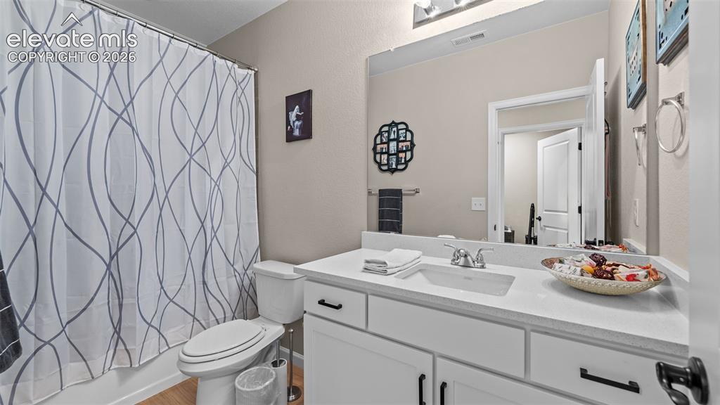 Image 32 of 46: White vanity with black hardware, white rectangular sink, light-toned count