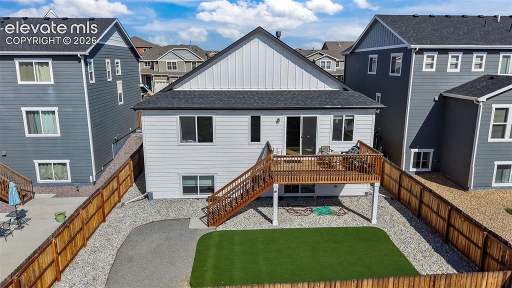 Image 34 of 46: Elevated wood deck with stairs, private fenced yard, artificial turf lawn, 