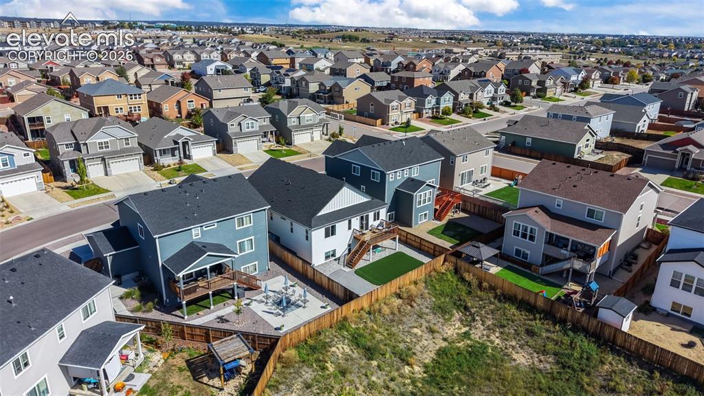 Image 38 of 46: Rear exterior featuring an elevated deck, artificial turf, and a fenced yar