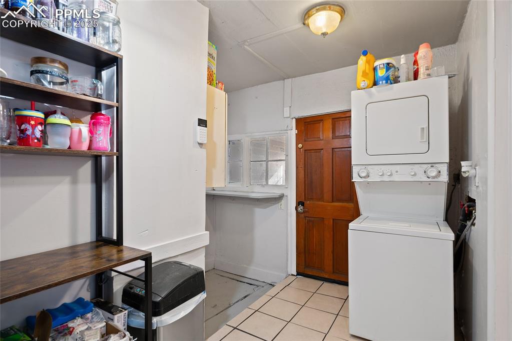 Image 23 of 26: Laundry room featuring light tile patterned flooring and stacked washer / d