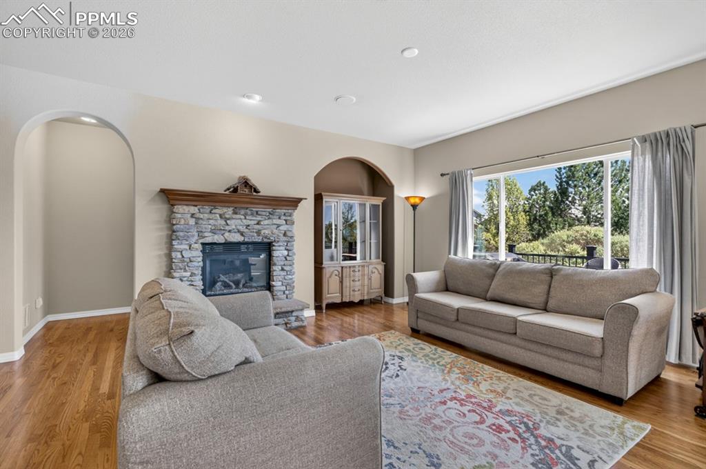 Image 12 of 47: Living area featuring a stone-faced fireplace with a wood mantel, wood-fini