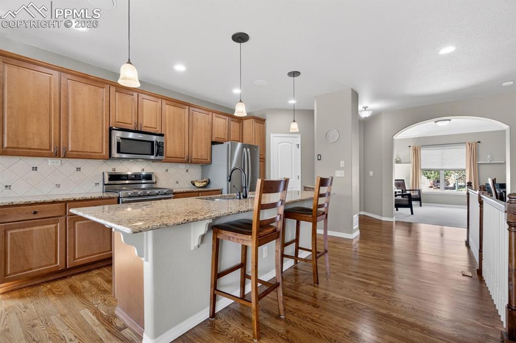 Image 13 of 47: Large granite island, stainless steel appliances, and a tiled backsplash. V