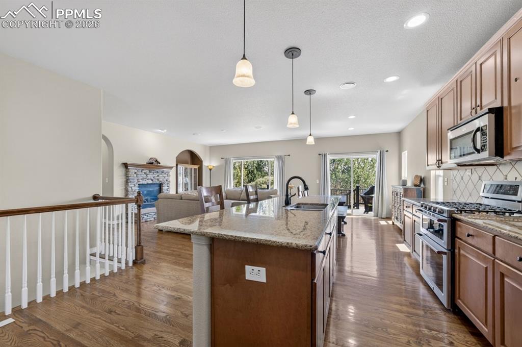 Image 15 of 47: Open-concept kitchen featuring an island with a sink, wood-finish flooring,