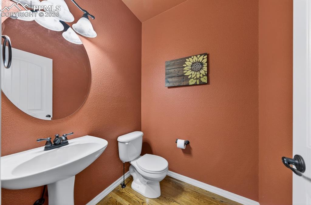 Image 19 of 47: Beautiful half bath on main floor with pedestal sink and circular mirror