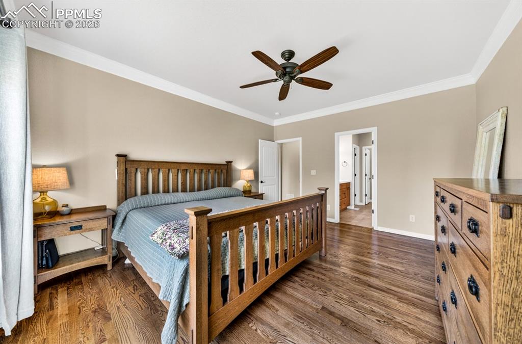 Image 21 of 47: Primary bedroom with hardwood flooring throughout the room, crown molding, 
