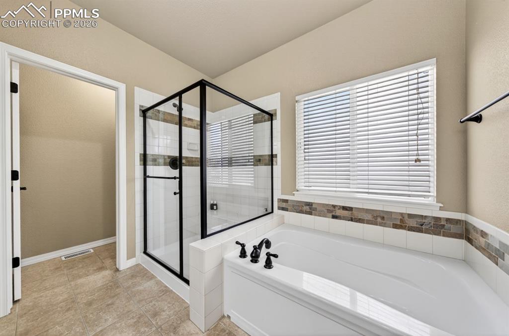 Image 25 of 47: Bathroom featuring an enclosed shower with black framing, a built-in soakin