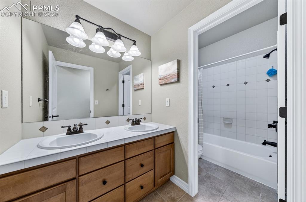 Image 27 of 47: Lower level bathroom featuring a dual vanity with wood-finish cabinetry and