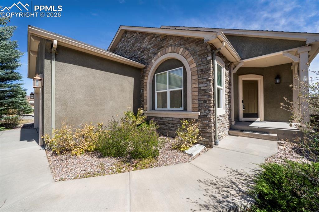 Image 3 of 47: Stone and stucco exterior featuring an arched window, covered entryway, and