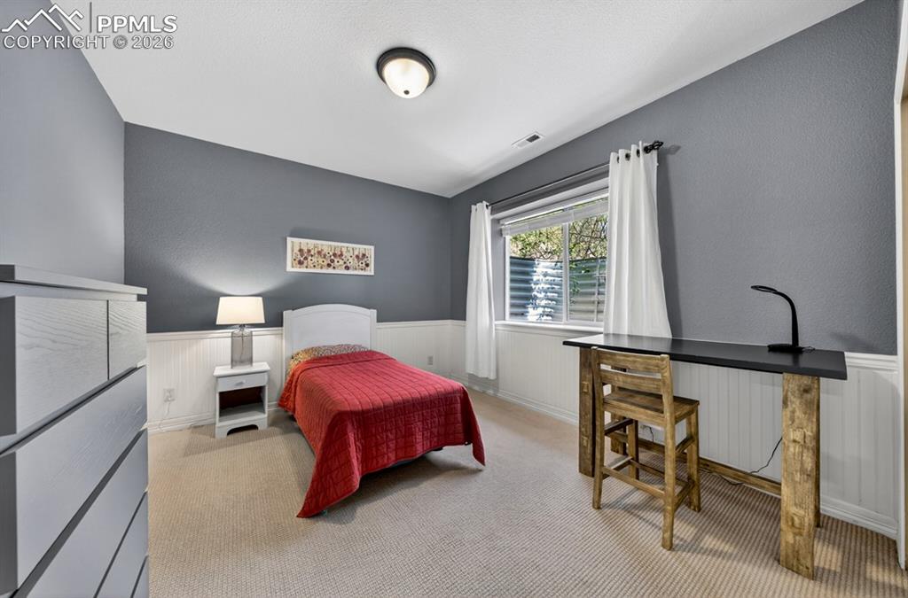 Image 30 of 47: Second of 3 bedrooms in lower level, with white wainscoting, and a ceiling-