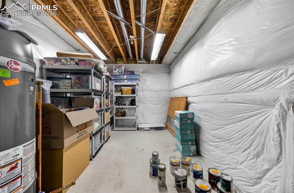 Image 36 of 47: Unfinished basement space featuring concrete flooring, water heater, and fl