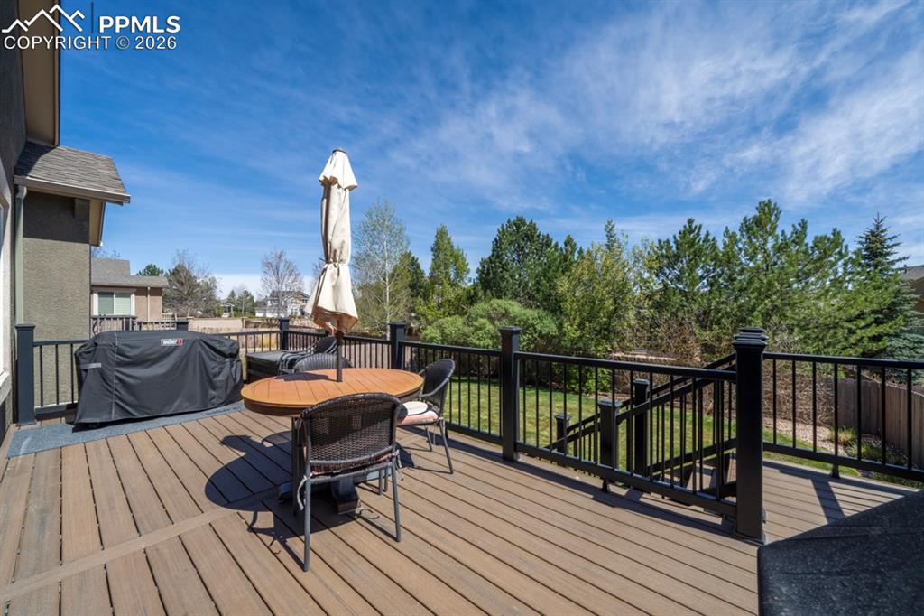 Image 40 of 47: Spacious exterior deck with stairs leading to the yard below.  Table and ch
