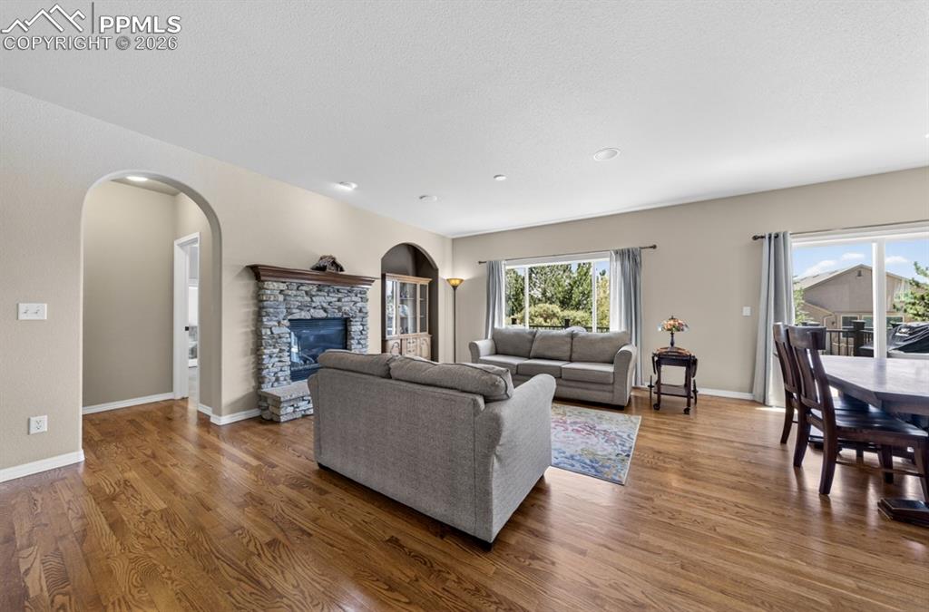 Image 8 of 47: Spacious living area featuring wood flooring, a stone-clad fireplace with a