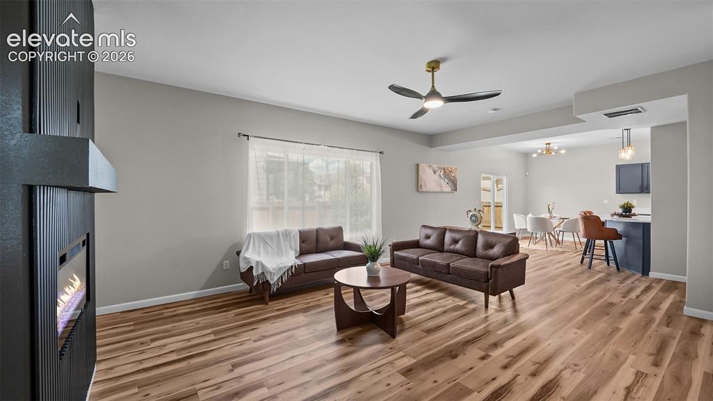 Image 11 of 47: Open-concept living space featuring wood-finish flooring, a contemporary fi