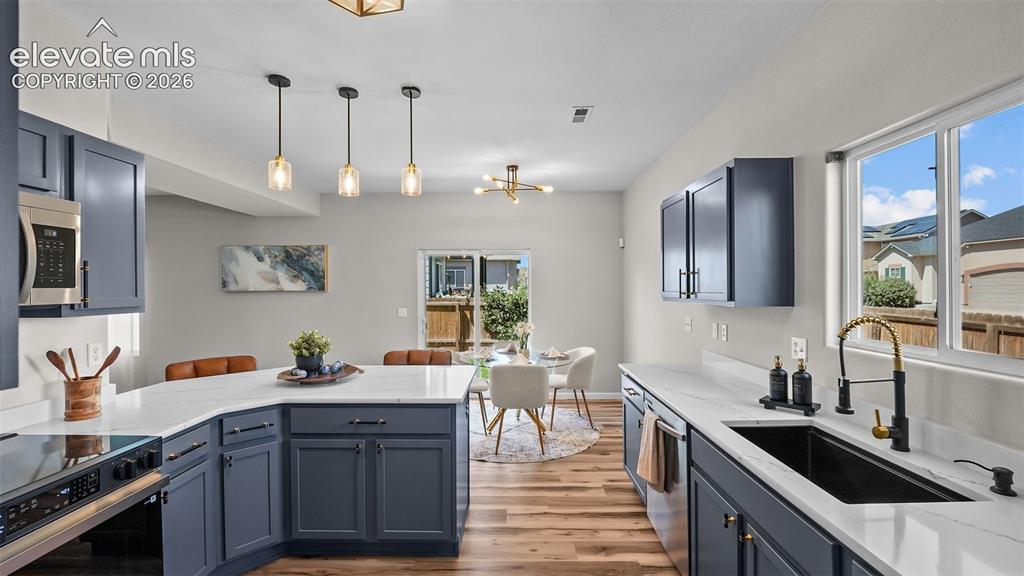 Image 12 of 47: Kitchen featuring dark blue cabinetry, white countertops, stainless steel a