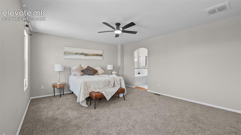 Image 21 of 47: Spacious bedroom featuring vaulted ceilings, a ceiling fan with integrated