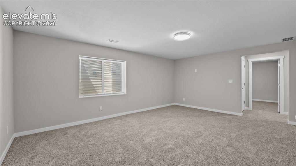 Image 27 of 47: Light-colored carpeting, neutral painted walls, and a window with blinds
