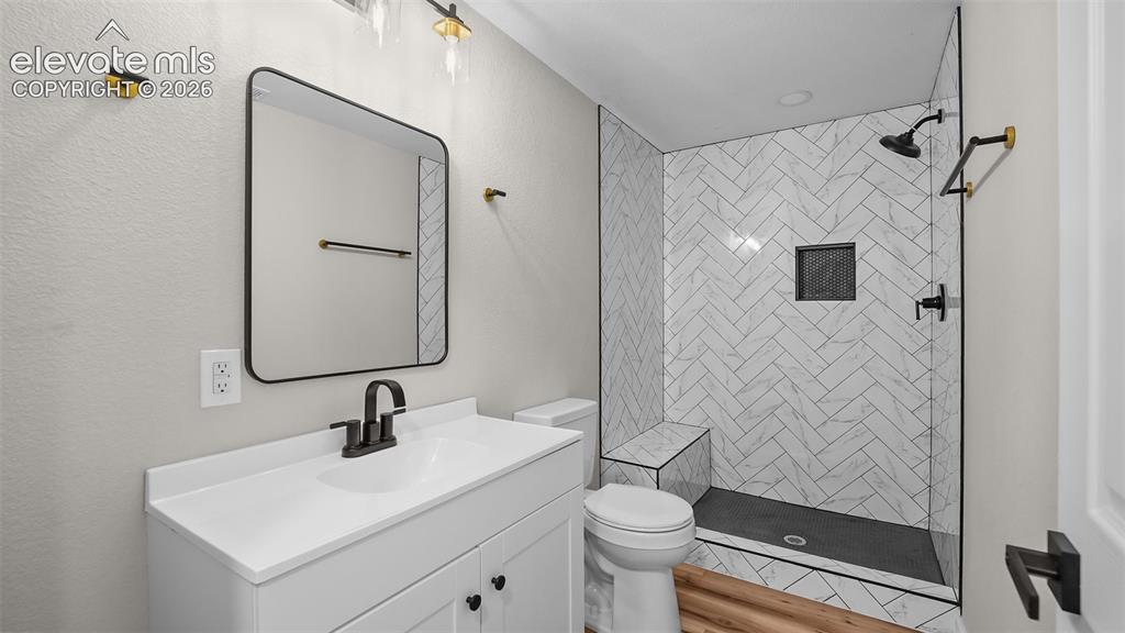 Image 30 of 47: White vanity with black hardware, rectangular framed mirror, and wood-finis