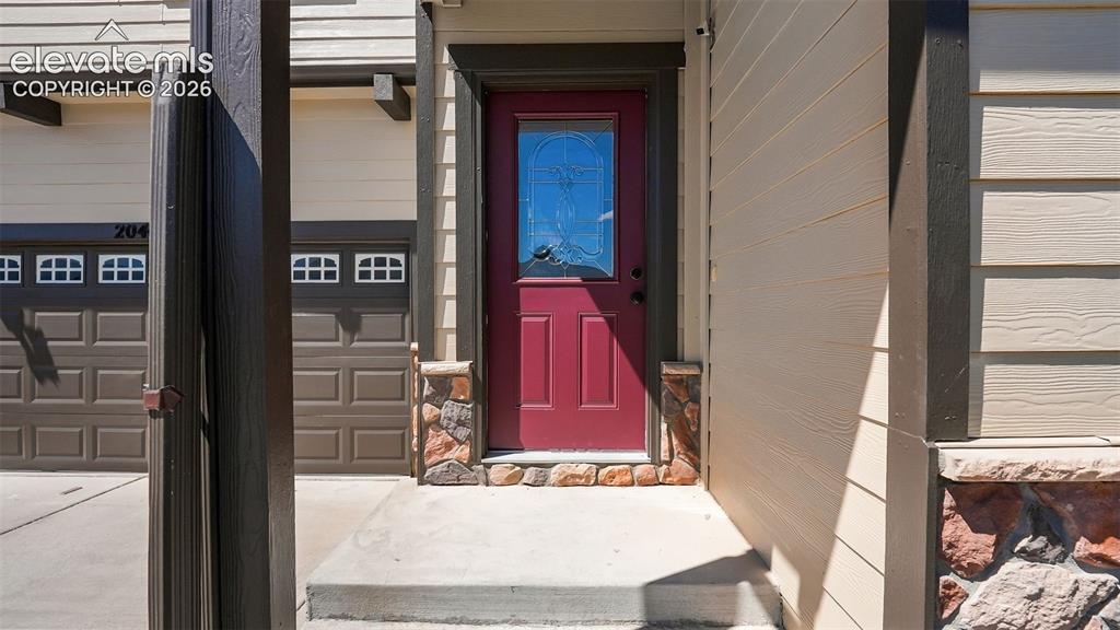 Image 4 of 47: Red entry door with decorative glass inlay, stone veneer accents, and horiz