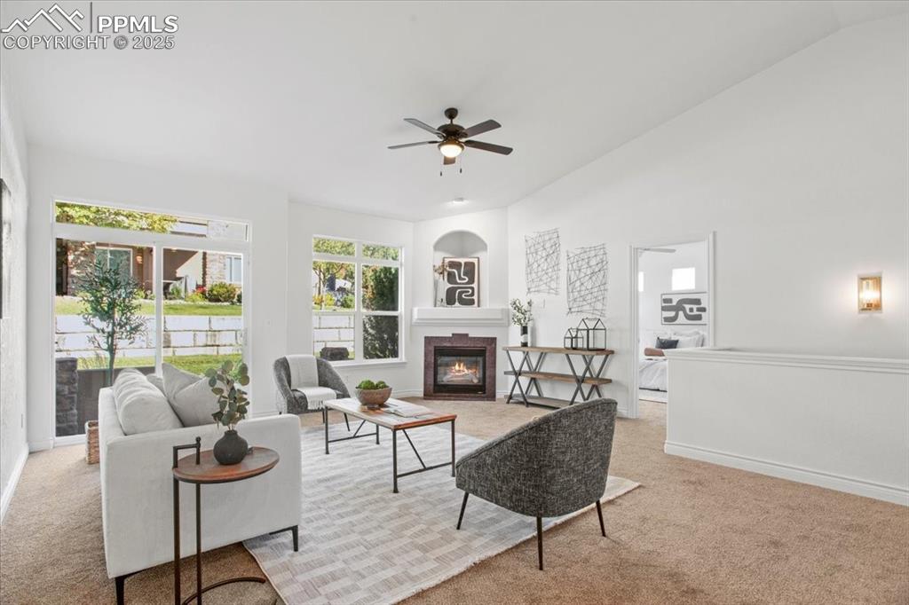 Image 10 of 31: Living room with light carpet, a glass covered fireplace, vaulted ceiling,