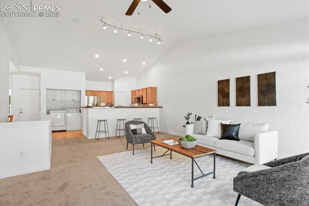 Image 2 of 31: Living area featuring light colored carpet, ceiling fan, independent washer
