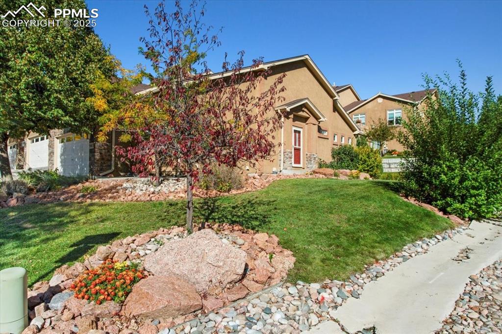 Image 23 of 31: View of front of house with a front lawn, stucco siding, and stone siding