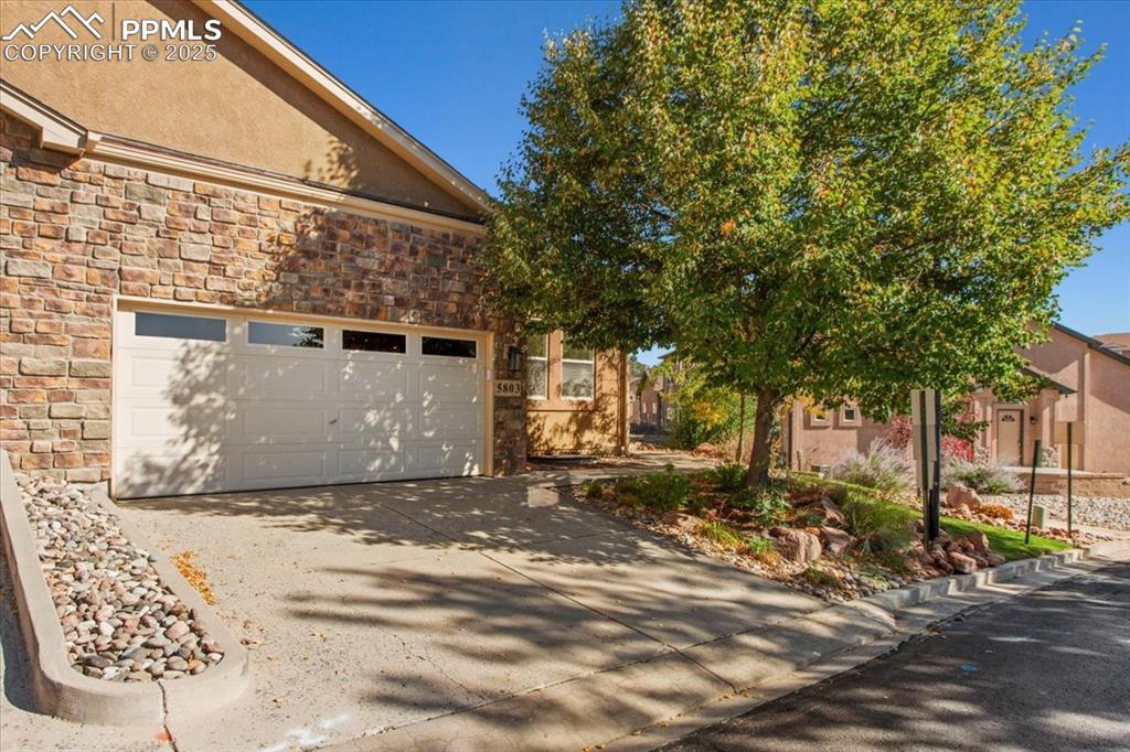 Image 25 of 31: View of property exterior featuring stone siding, concrete driveway, stucco