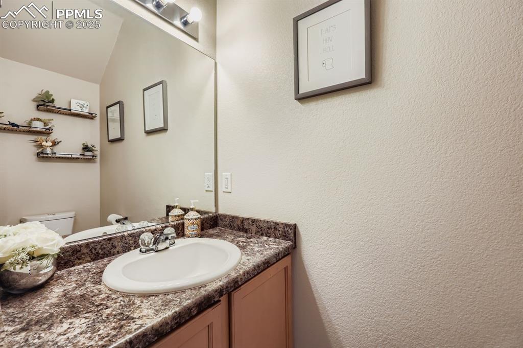 Image 13 of 27: Half bath with vanity and a textured wall