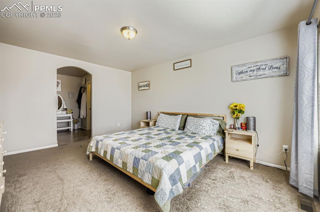 Image 14 of 27: Bedroom featuring arched walkways and carpet
