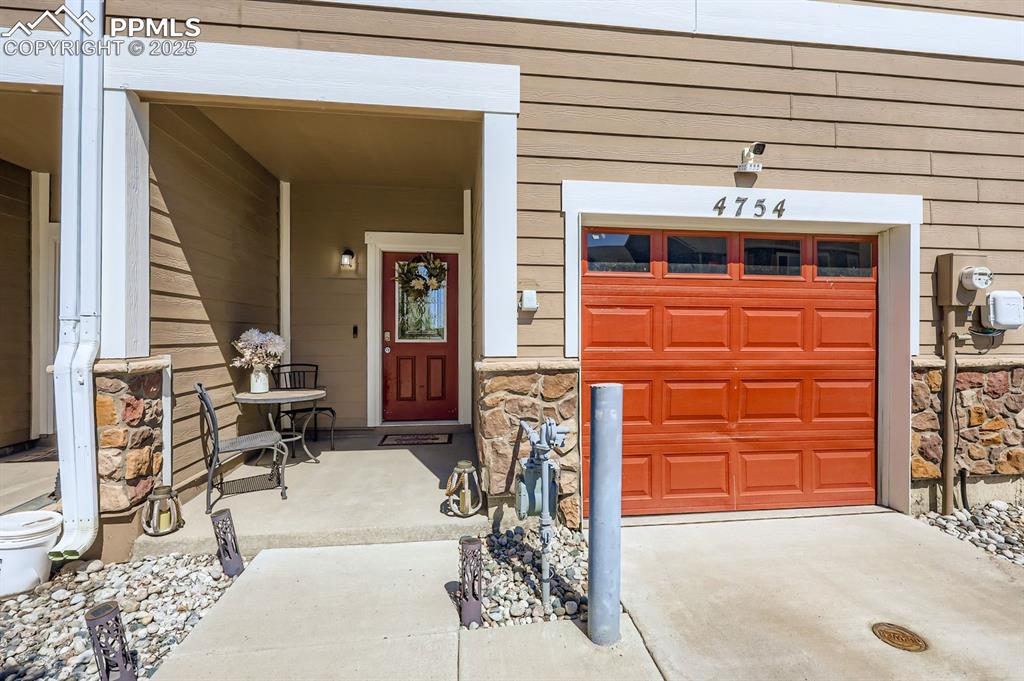 Image 3 of 27: Entrance to property featuring stone siding, a porch, and a garage
